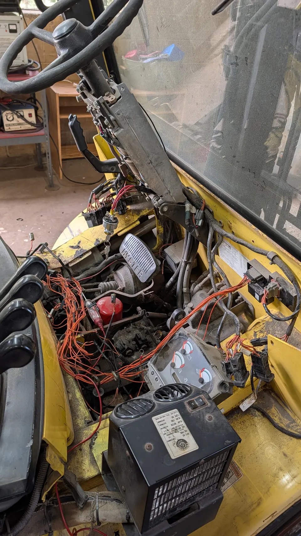 Exposed wiring, steering column, and dashboard components during forklift repair