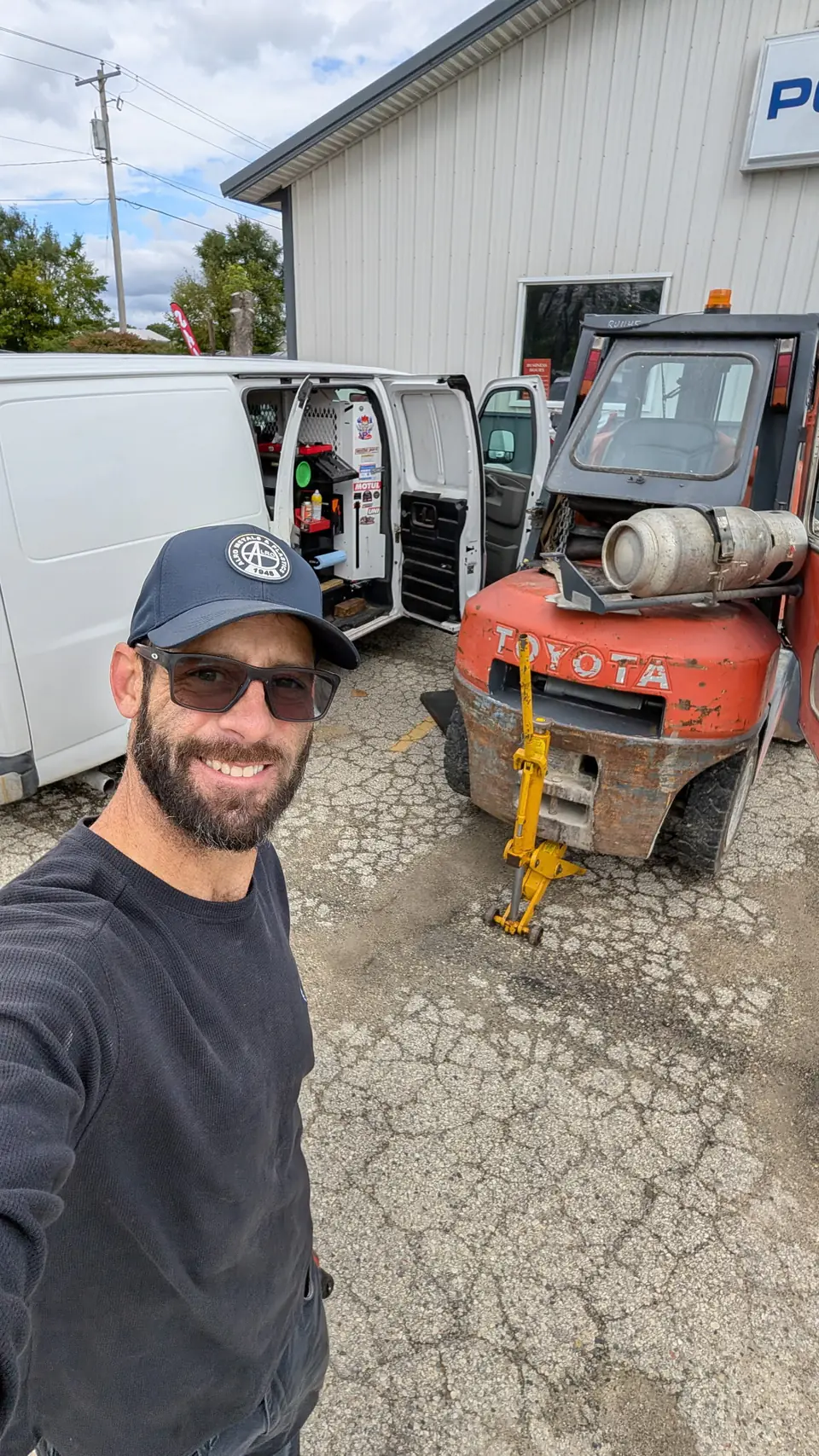 Technician beside a Toyota forklift and the open service van